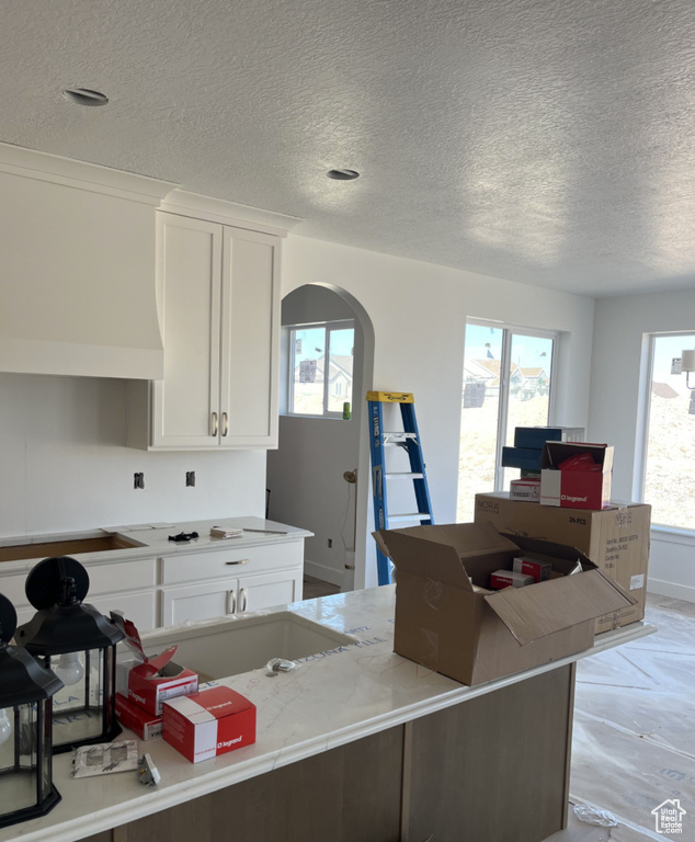 Kitchen with white cabinets, a textured ceiling, and plenty of natural light