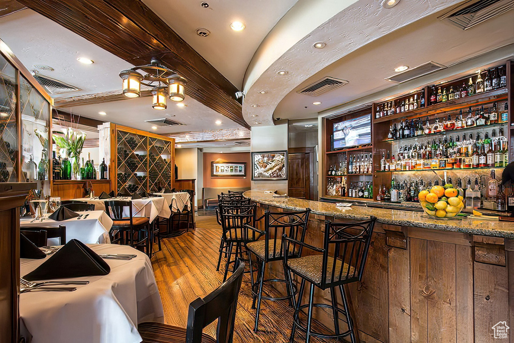 Bar featuring hardwood / wood-style floors and stone countertops