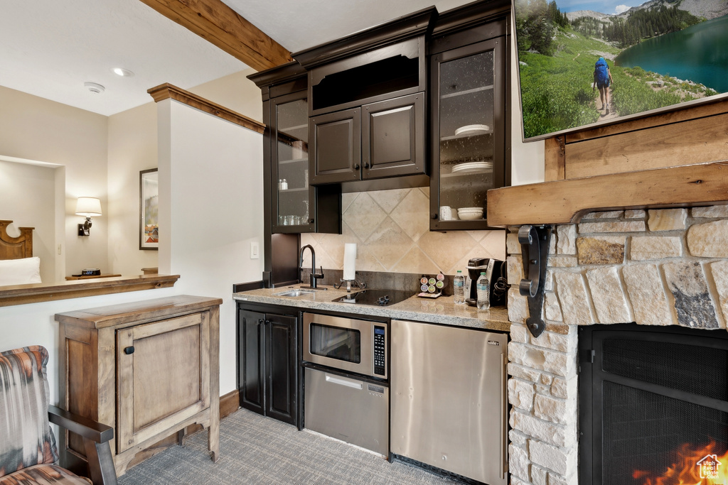 Kitchen with a fireplace, tasteful backsplash, light carpet, stainless steel microwave, and refrigerator