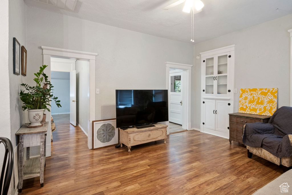 Living room with built in features, ceiling fan, and hardwood / wood-style floors