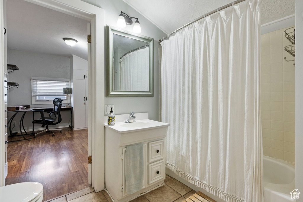 Full bathroom featuring vanity, hardwood / wood-style floors, shower / bath combo, toilet, and lofted ceiling