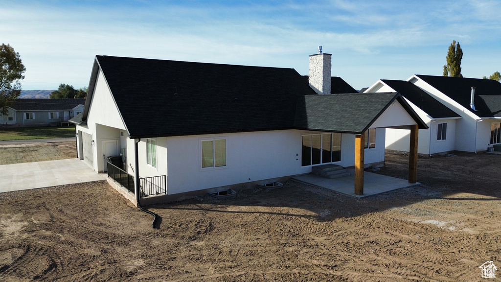 Back of property with a garage and a patio