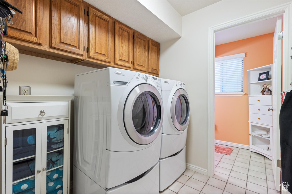 Laundry room with cabinets, washing machine and dryer, and light tile patterned floors