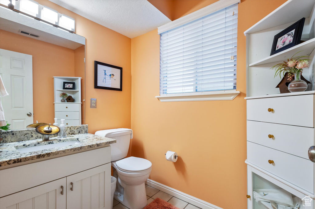 Bathroom with tile patterned flooring, toilet, vanity, and a textured ceiling