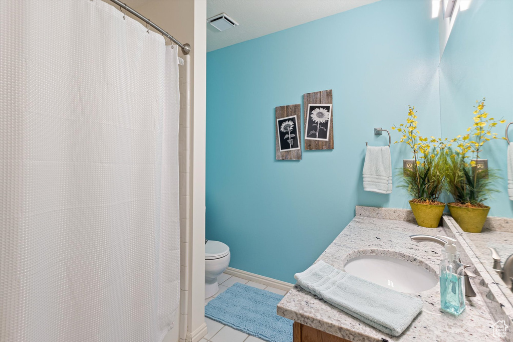 Bathroom featuring vanity, tile patterned flooring, and toilet