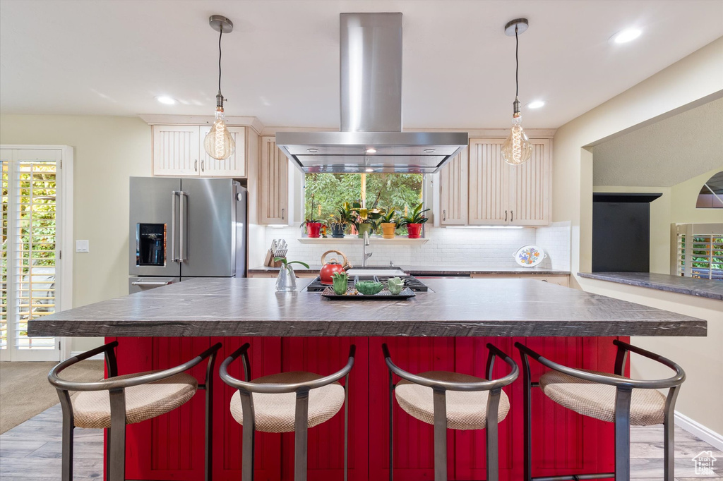 Kitchen featuring high quality fridge, light hardwood / wood-style flooring, island range hood, and decorative backsplash