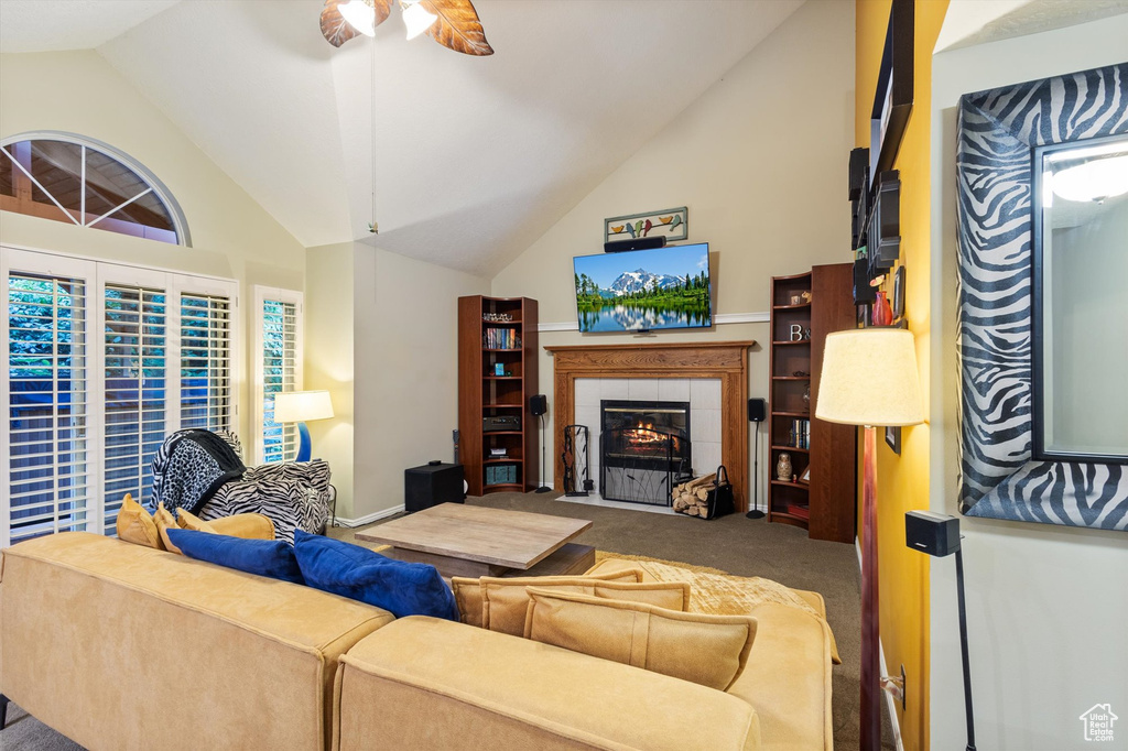 Living room featuring a fireplace, high vaulted ceiling, carpet floors, and ceiling fan