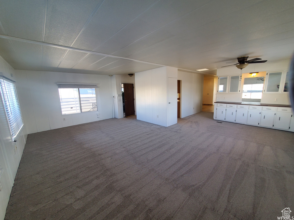 Unfurnished living room with ceiling fan and light colored carpet