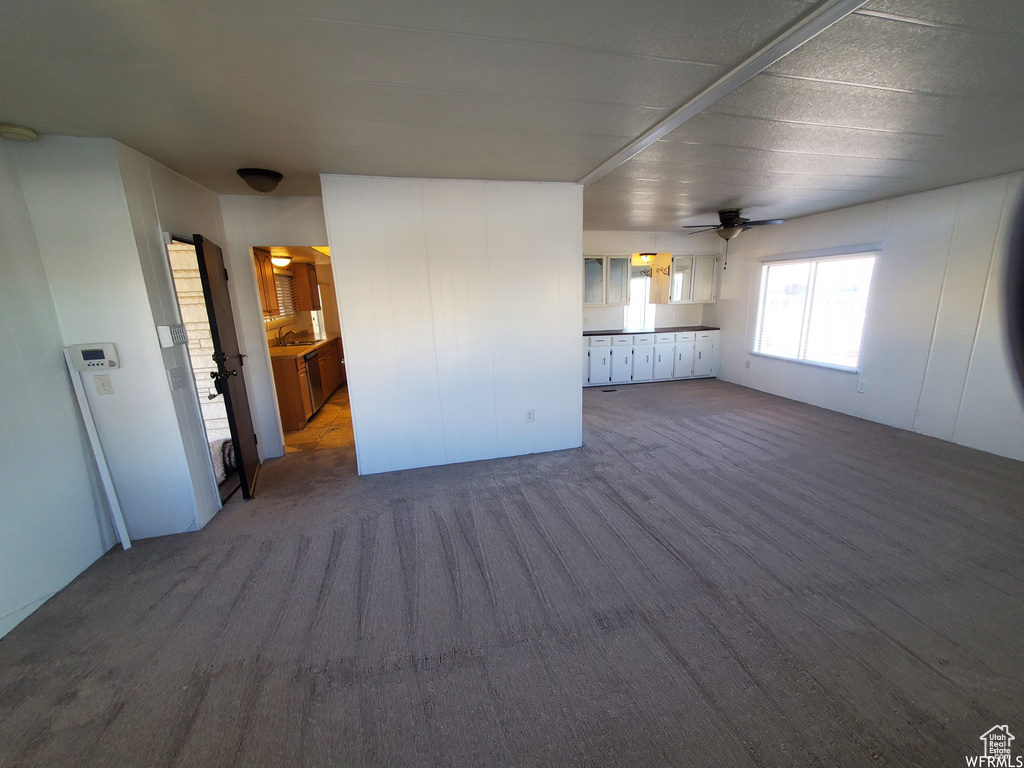 Unfurnished living room with carpet, sink, and ceiling fan