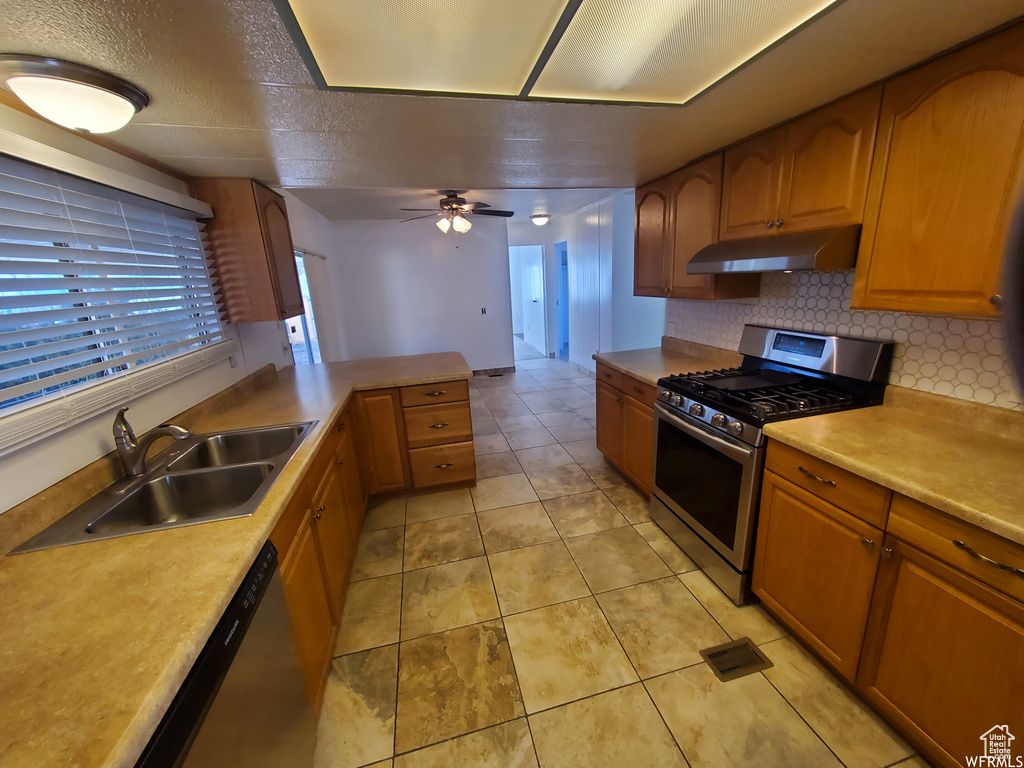 Kitchen featuring light tile patterned flooring, tasteful backsplash, ceiling fan, stainless steel gas stove, and sink