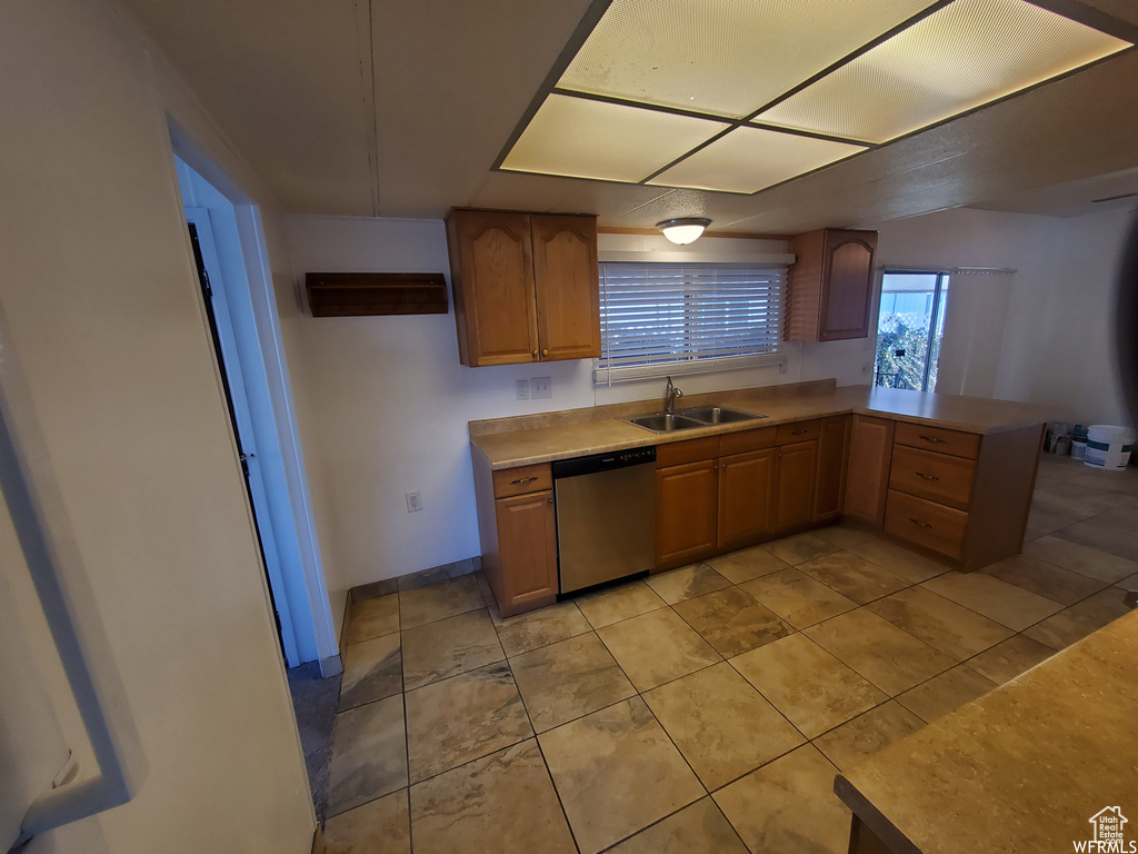 Kitchen featuring light tile patterned floors, dishwasher, sink, and kitchen peninsula