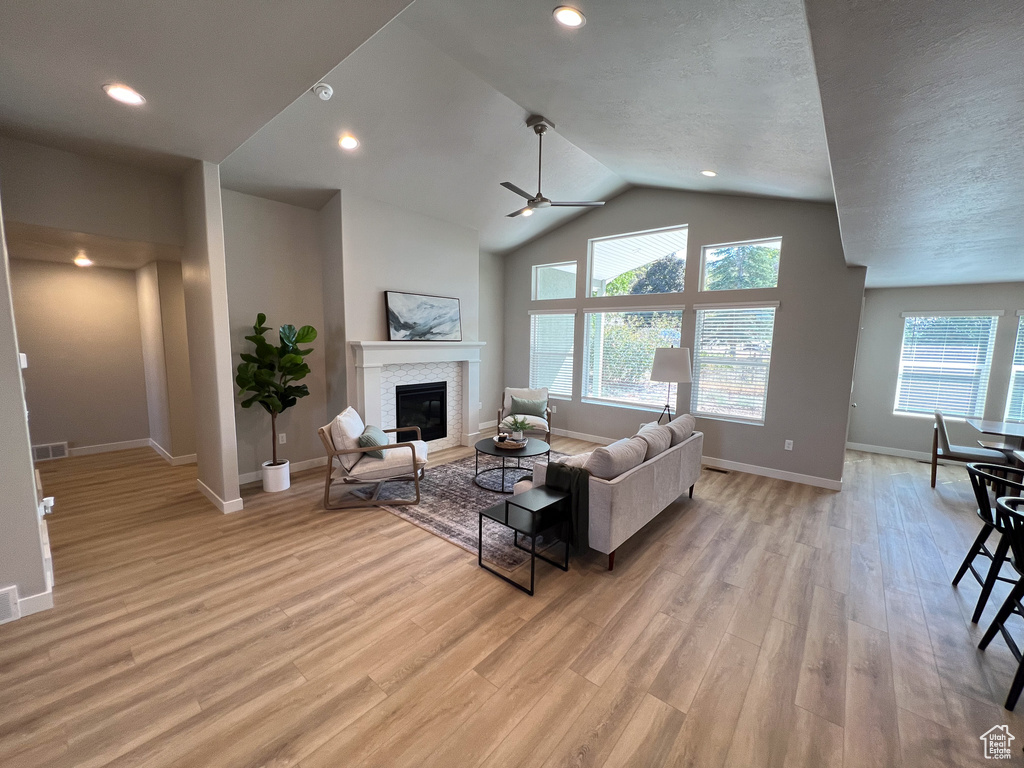 Living room featuring ceiling fan, light hardwood / wood-style floors, a textured ceiling, and vaulted ceiling