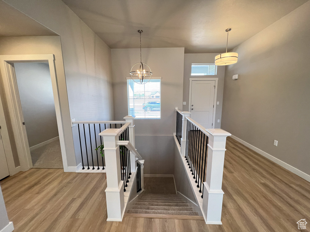 Stairs with an inviting chandelier and hardwood / wood-style floors