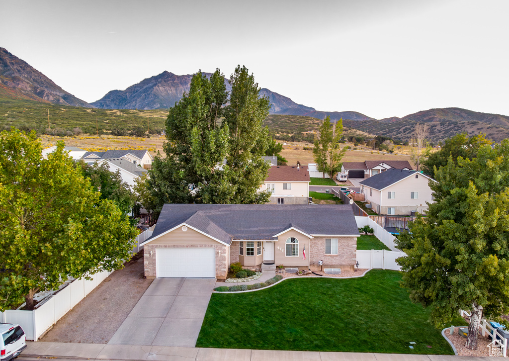 Exterior space with a garage, a front lawn, and a mountain view