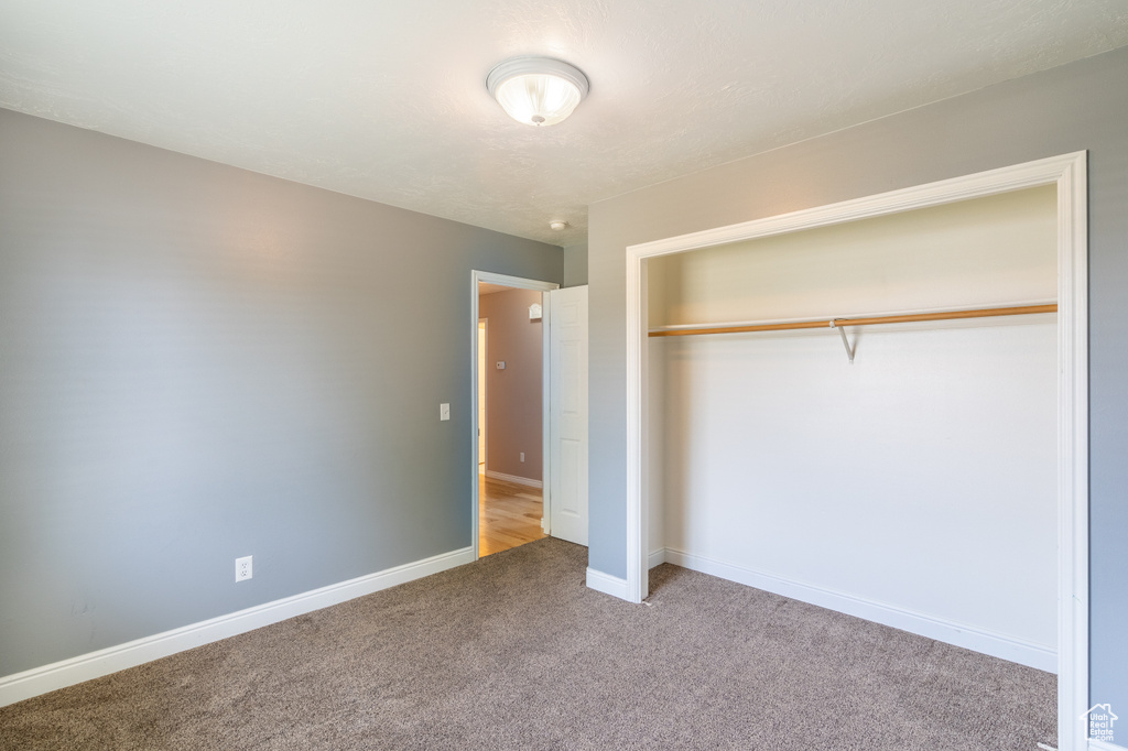 Unfurnished bedroom with light carpet and a closet