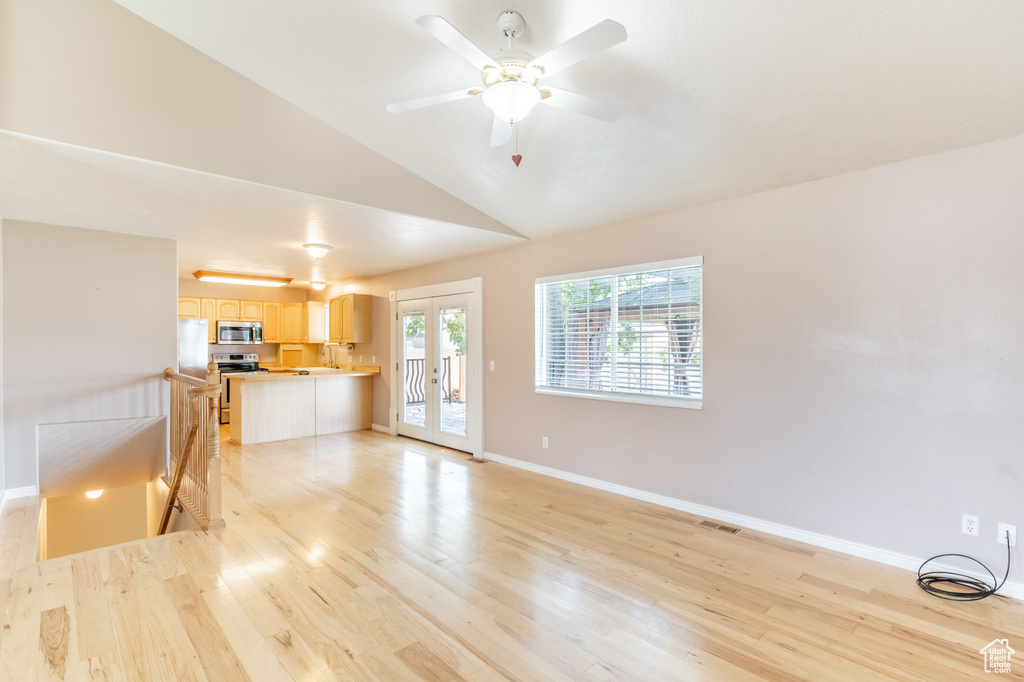 Unfurnished living room with lofted ceiling, french doors, light wood-type flooring, and ceiling fan