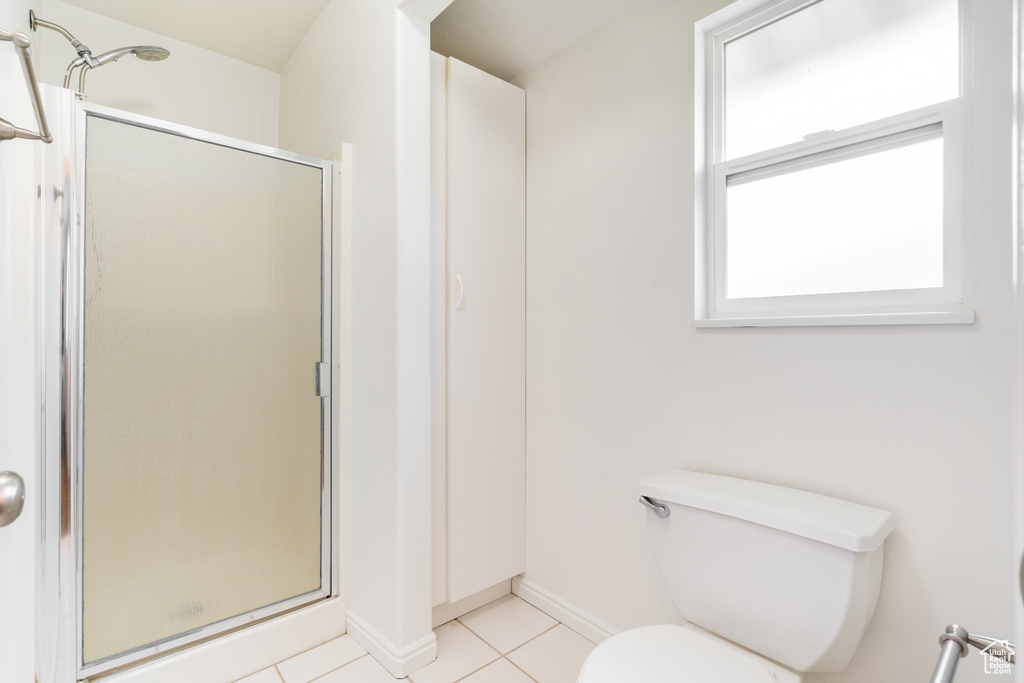 Bathroom featuring walk in shower, tile patterned floors, and toilet