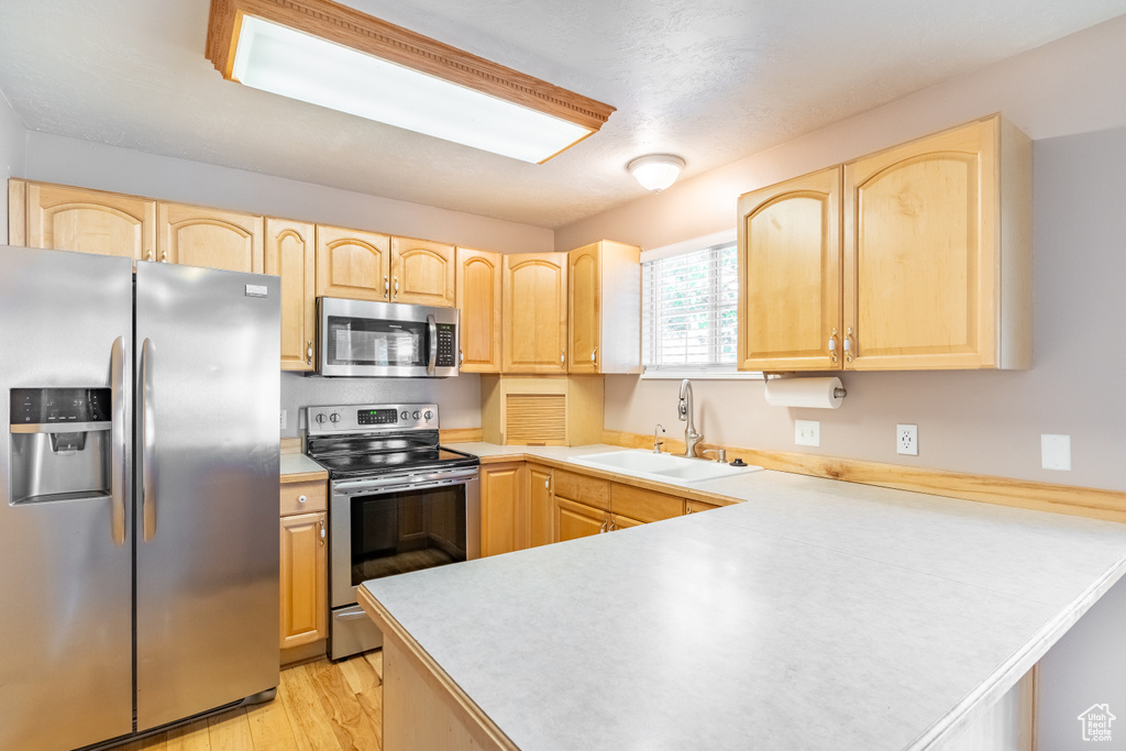 Kitchen featuring light hardwood / wood-style floors, appliances with stainless steel finishes, sink, and light brown cabinets