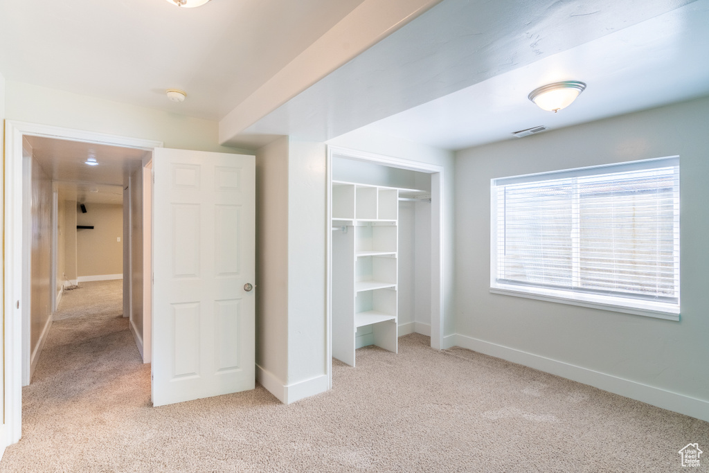 Unfurnished bedroom with light carpet and a closet