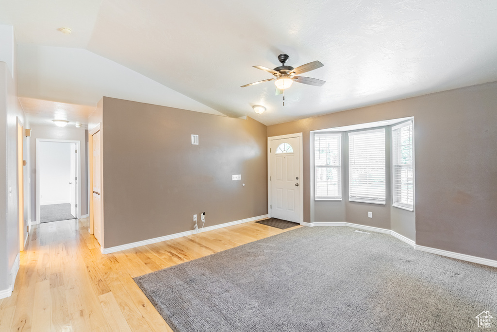 Entryway with lofted ceiling, light colored carpet, and ceiling fan