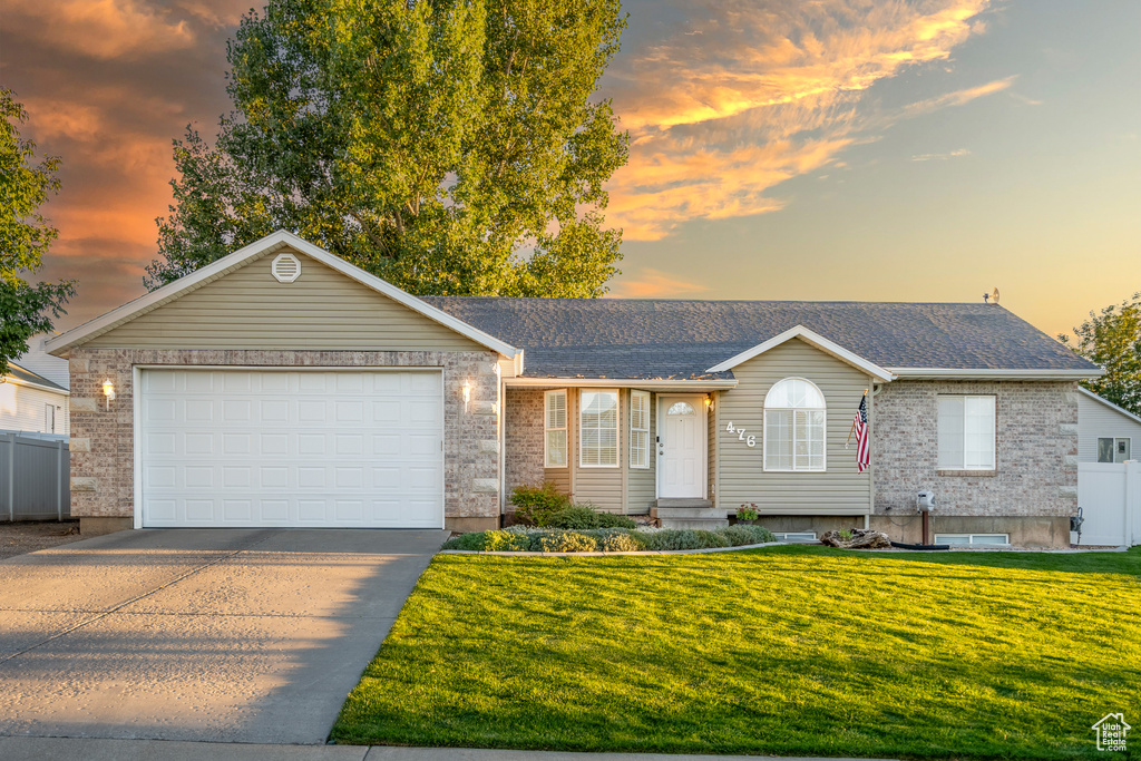 Ranch-style home featuring a garage and a lawn