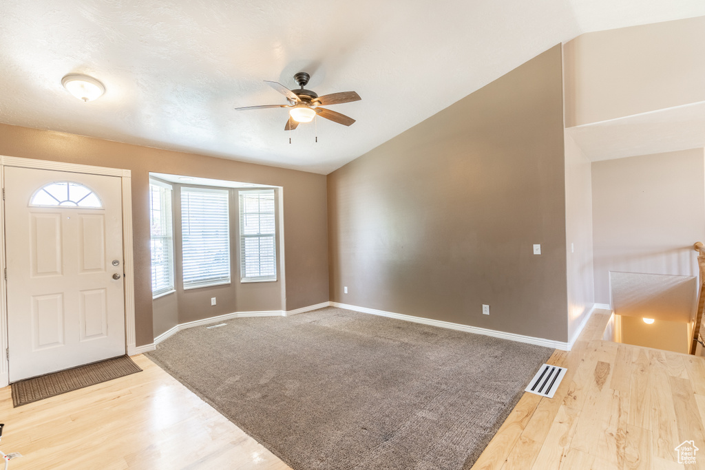 Foyer featuring lofted ceiling, light colored carpet, and ceiling fan