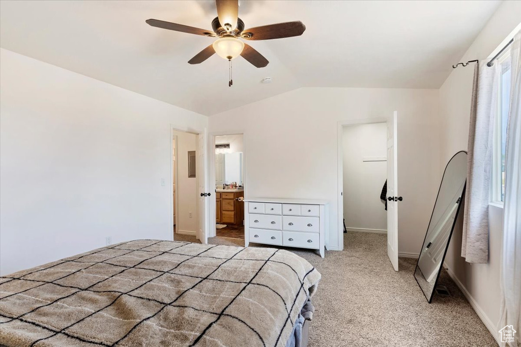 Bedroom with light colored carpet, connected bathroom, ceiling fan, and lofted ceiling