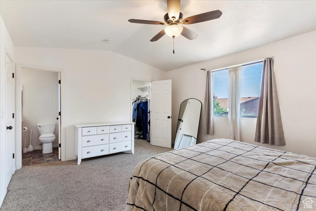 Bedroom featuring a spacious closet, a closet, vaulted ceiling, light carpet, and ceiling fan