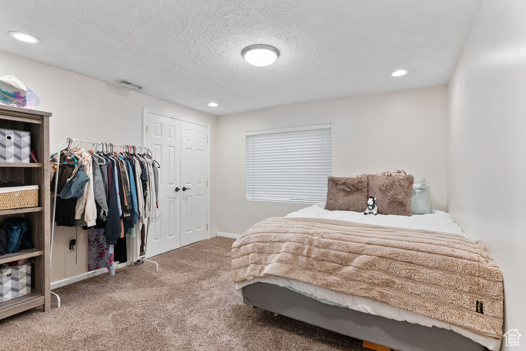 Carpeted bedroom with a textured ceiling and a closet