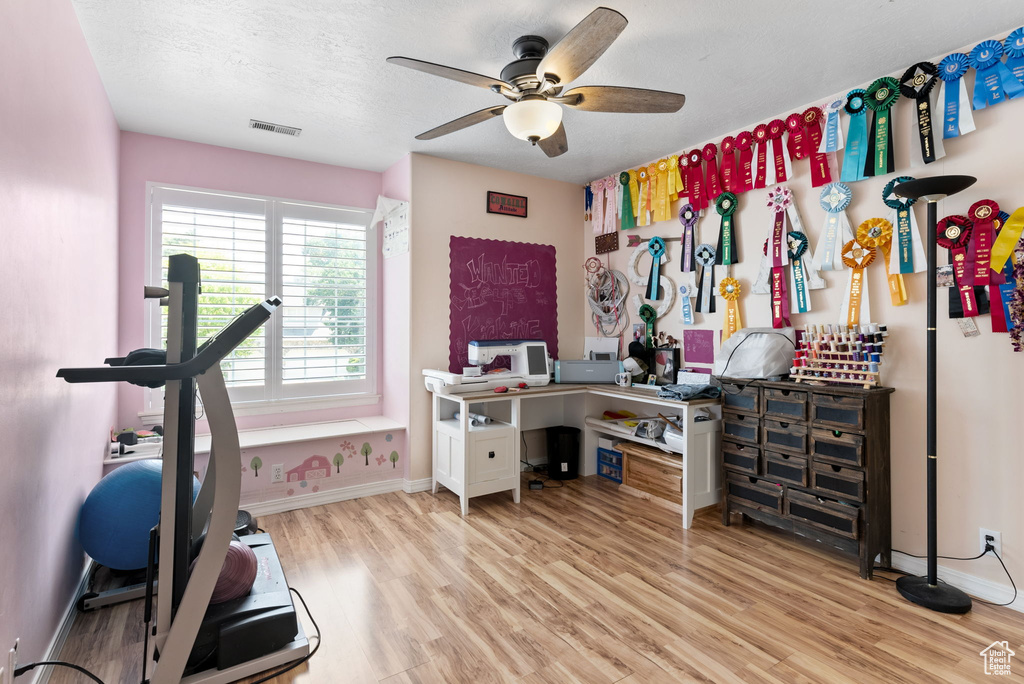 Home office featuring light hardwood / wood-style floors, a textured ceiling, and ceiling fan