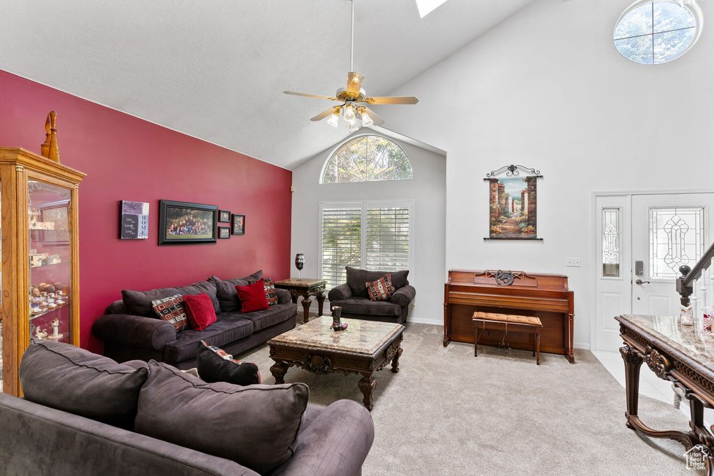 Carpeted living room featuring ceiling fan and high vaulted ceiling