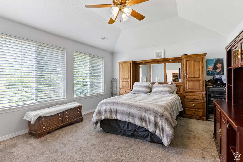 Bedroom with light carpet, ceiling fan, and vaulted ceiling