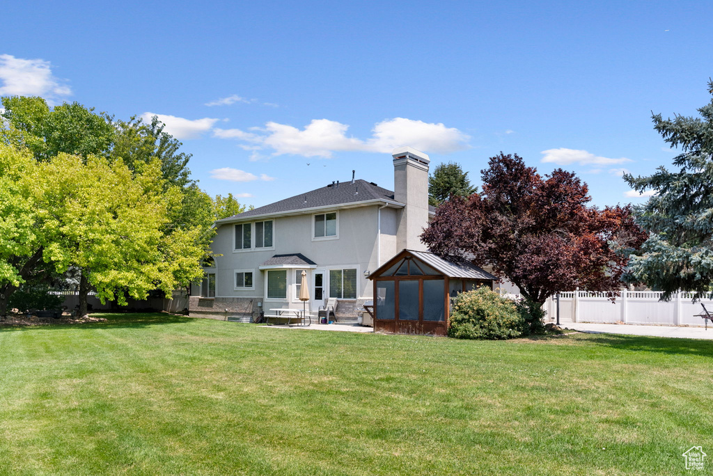 Back of house with a patio area and a lawn