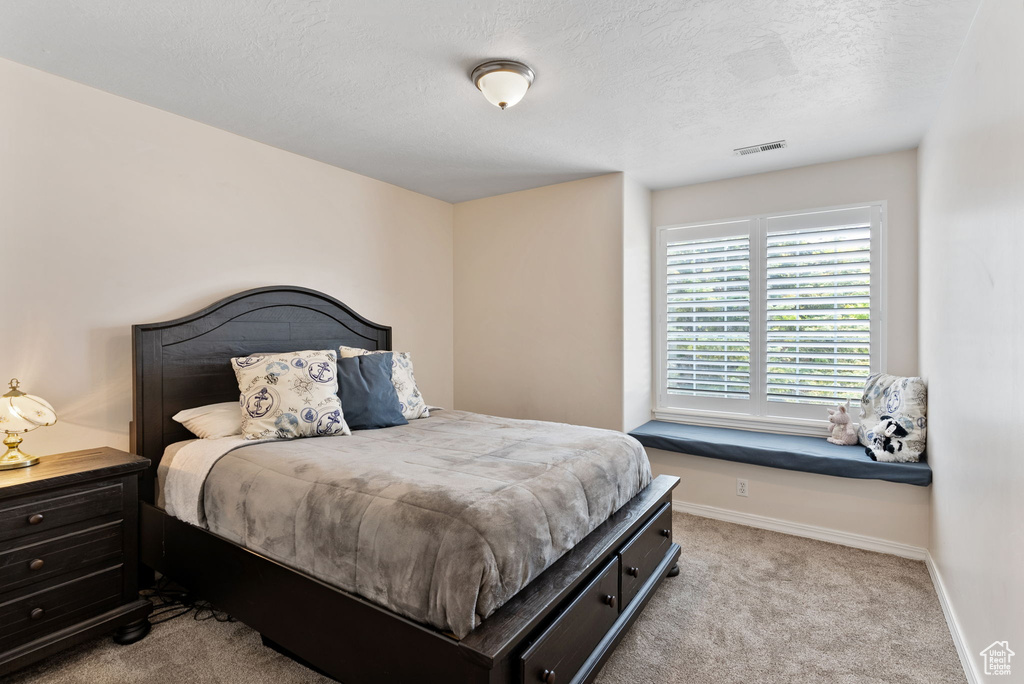 Bedroom with a textured ceiling and light colored carpet