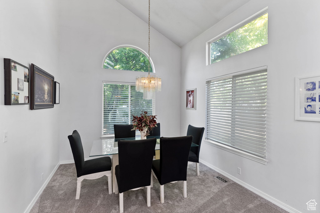 Carpeted dining room featuring an inviting chandelier and high vaulted ceiling