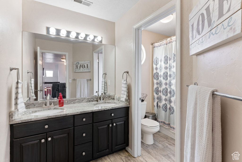 Bathroom with hardwood / wood-style floors, toilet, and dual bowl vanity