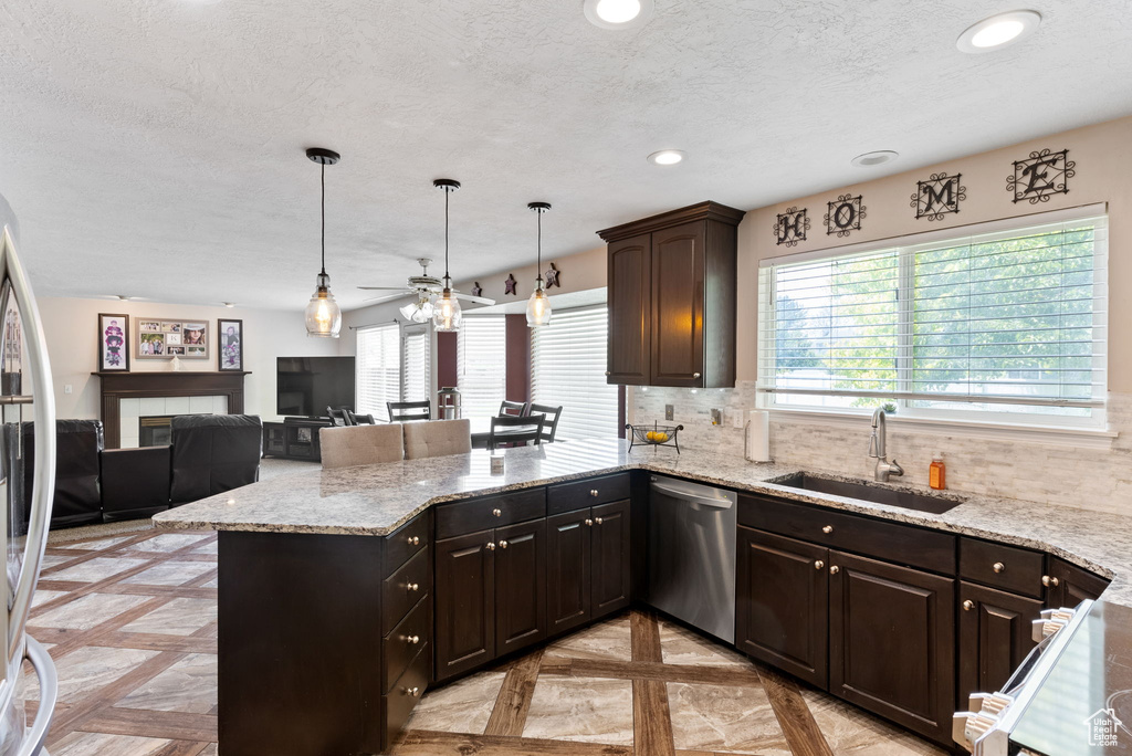 Kitchen featuring stainless steel dishwasher, tasteful backsplash, light parquet flooring, sink, and kitchen peninsula