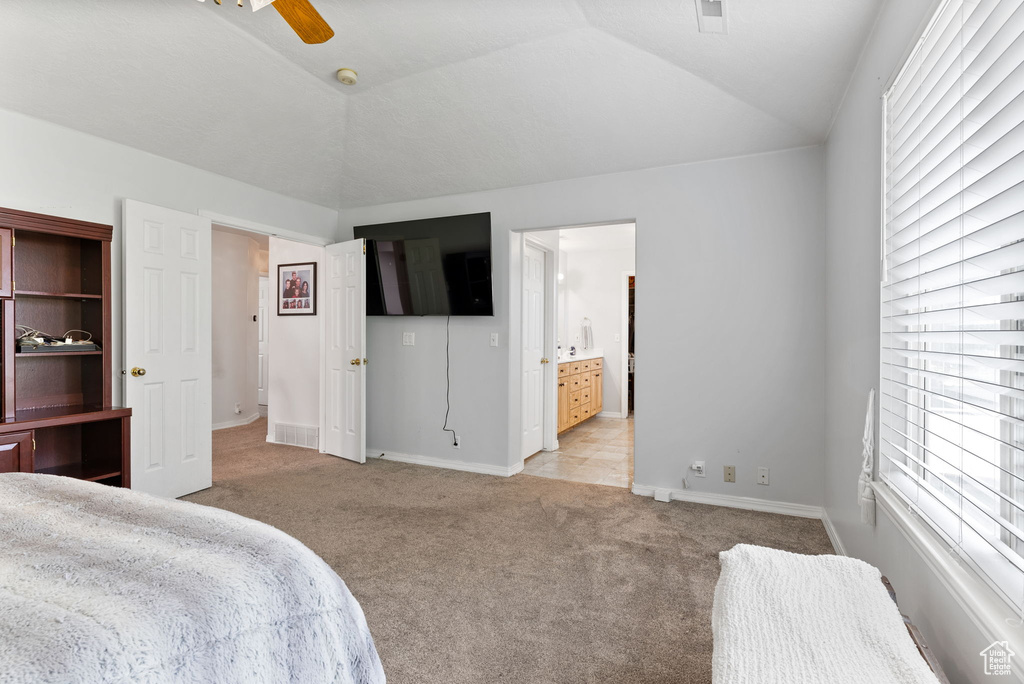 Tiled bedroom featuring multiple windows, ceiling fan, and vaulted ceiling