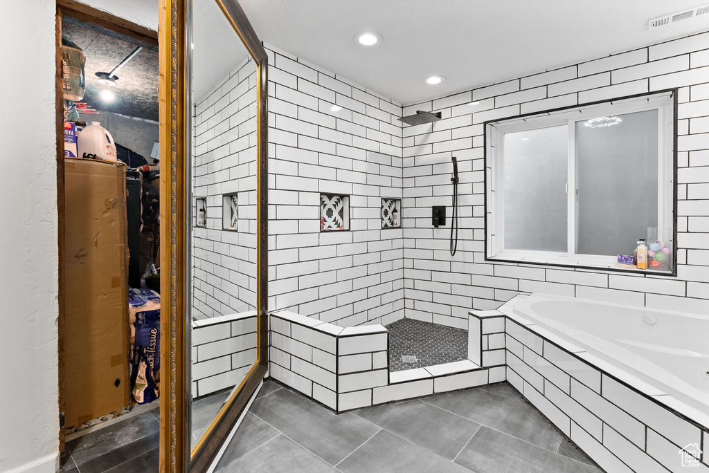 Bathroom with tile patterned flooring, tile walls, and independent shower and bath