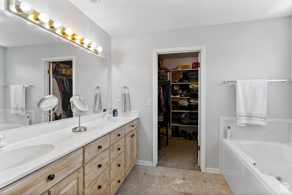 Bathroom featuring tile patterned flooring, a bathing tub, and double vanity