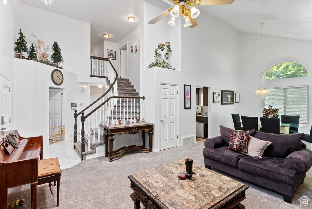 Carpeted living room with ceiling fan and high vaulted ceiling