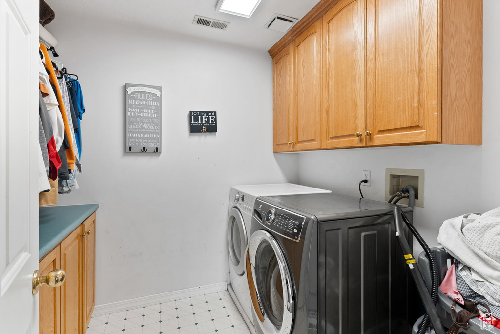 Laundry room featuring cabinets, washer and dryer, and light tile patterned floors