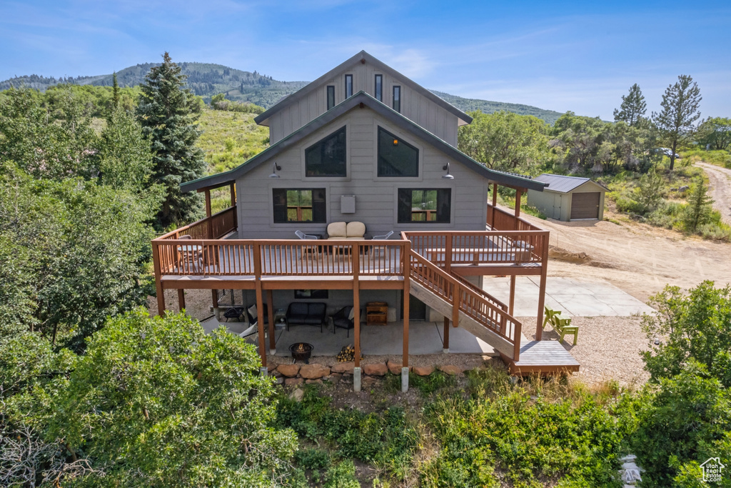 Rear view of house featuring a patio area, a storage unit, and a deck with mountain view