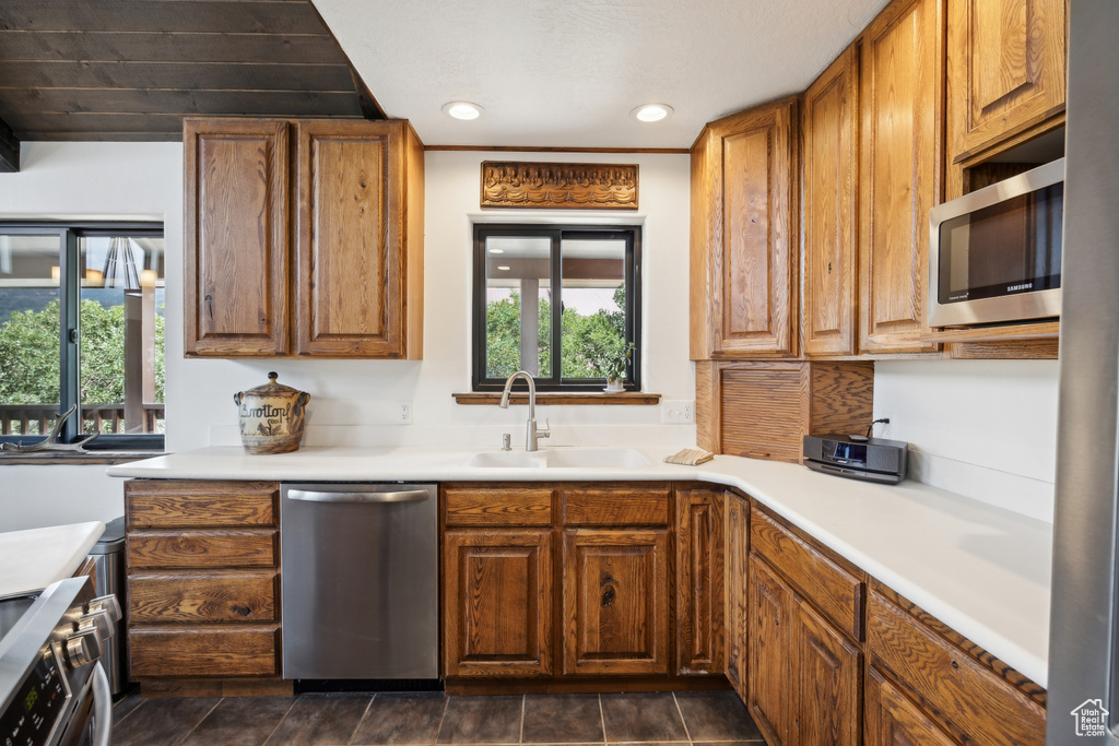 Kitchen with sink, dark tile patterned floors, and stainless steel appliances