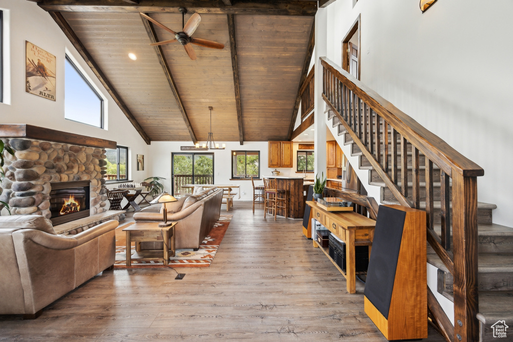 Living room with a fireplace, wood-type flooring, ceiling fan, beam ceiling, and wood ceiling