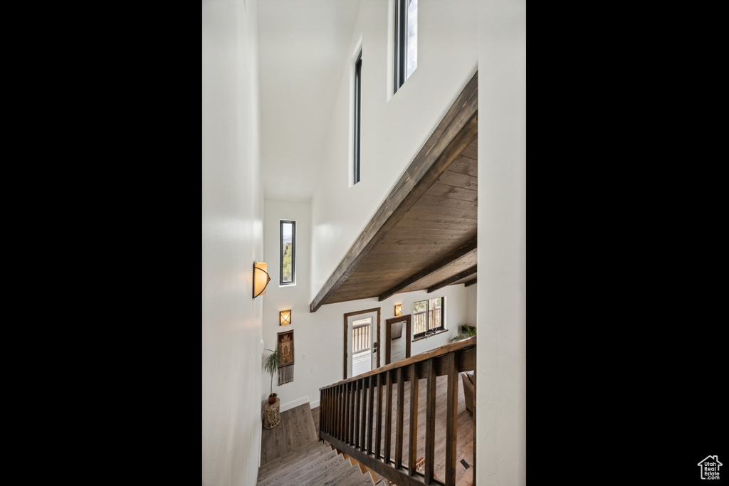 Stairs featuring beamed ceiling, wood ceiling, hardwood / wood-style floors, and a high ceiling