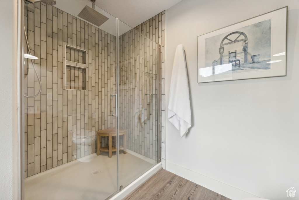 Bathroom with a shower with shower door, toilet, and hardwood / wood-style floors