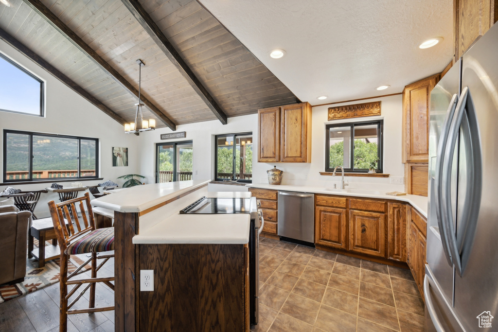 Kitchen featuring lofted ceiling with beams, a kitchen island, stainless steel appliances, and a healthy amount of sunlight