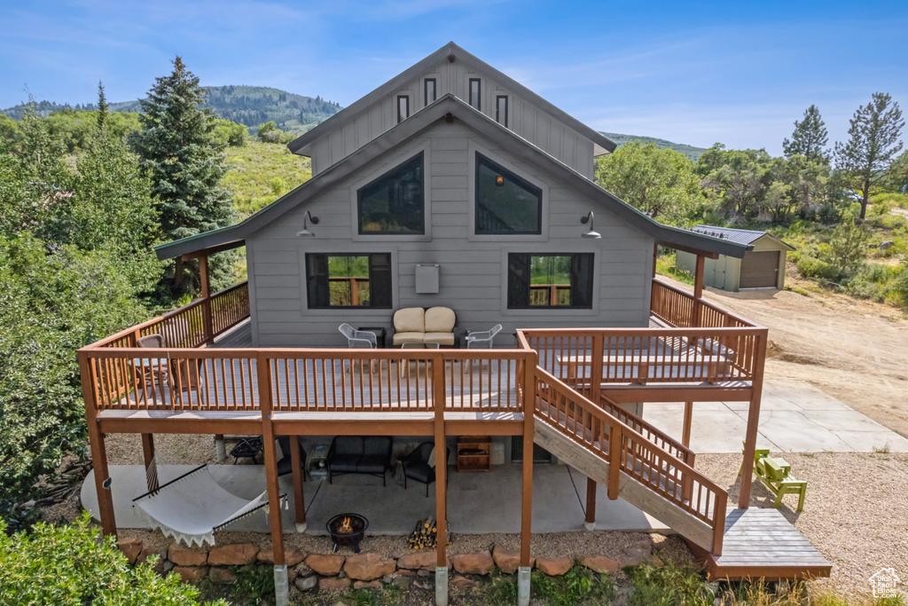 Rear view of property featuring a patio, a deck with mountain view, and a shed