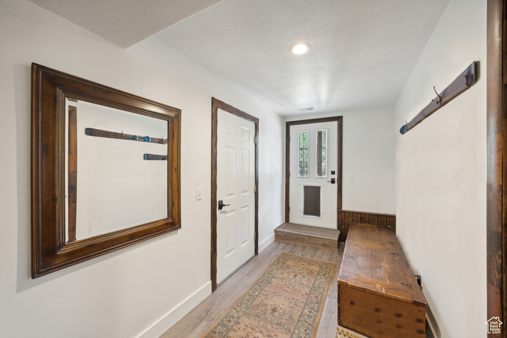 Doorway with light hardwood / wood-style floors and a textured ceiling